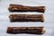 Three soft bully sticks. Dried beef esophagus Â  for pets. Horizontal layout option. White background. Shooting from above. Macro.
